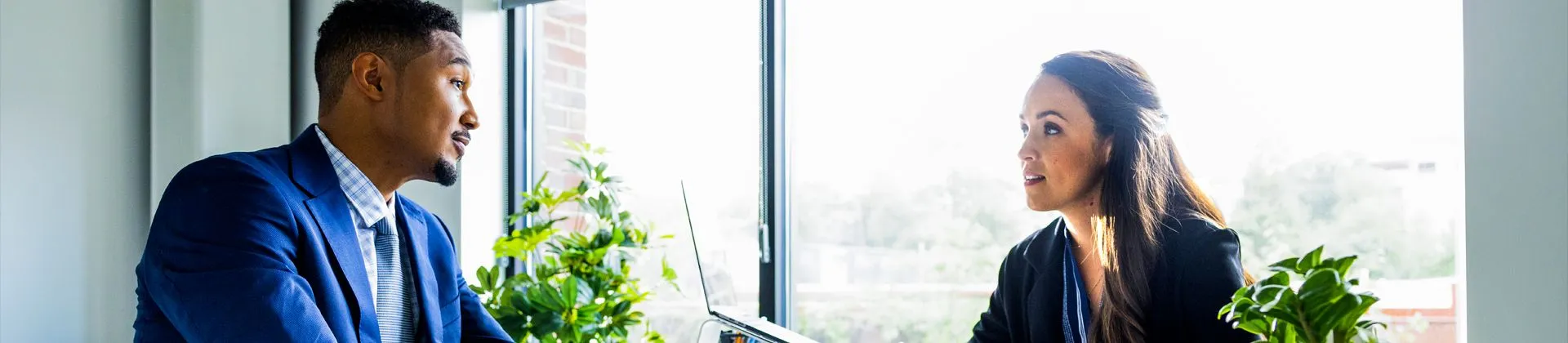 two people sitting in office with big window behind them