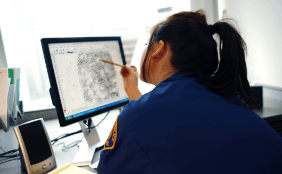 police officer examining fingerprints on computer monitor