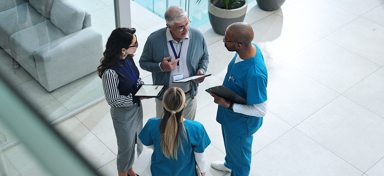 four people stand in a circle at a hospital talking
