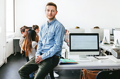 guy in blue button up shirt sitting on desk