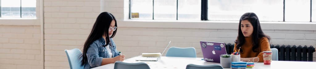 two women working on laptops in a shared space