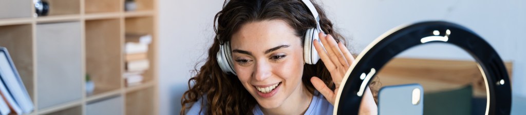 woman with headphones and a ring light recording video