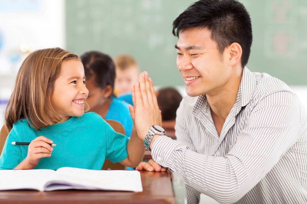 teacher high fiving a young student