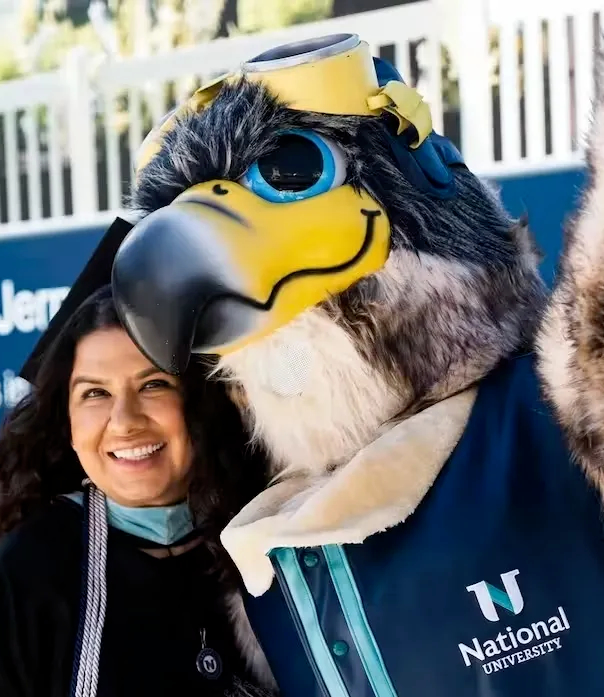 student and NU mascot Navi celebrating at graduation