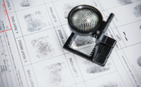 close up of magnifying glass on top of fingerprint papers