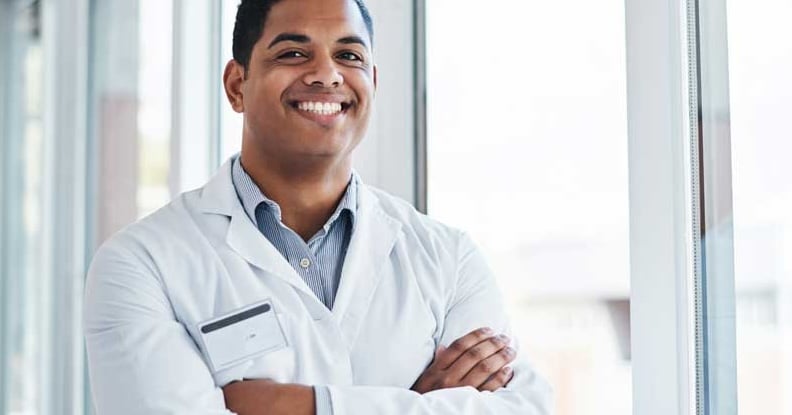 man in a white lab coat stands in a hospital