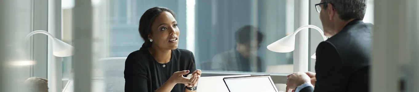 two people sitting in office with glass walls
