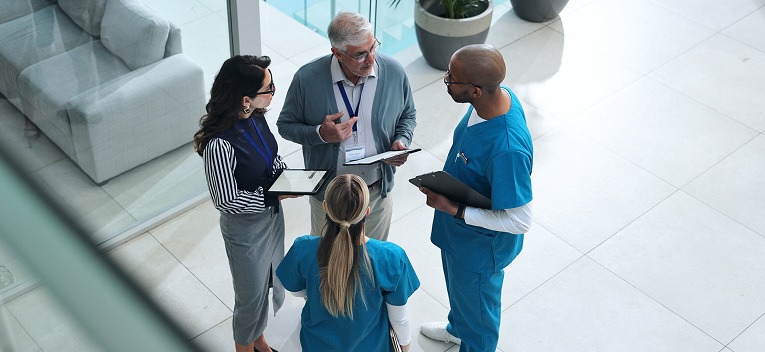 four people stand in a circle at a hospital talking