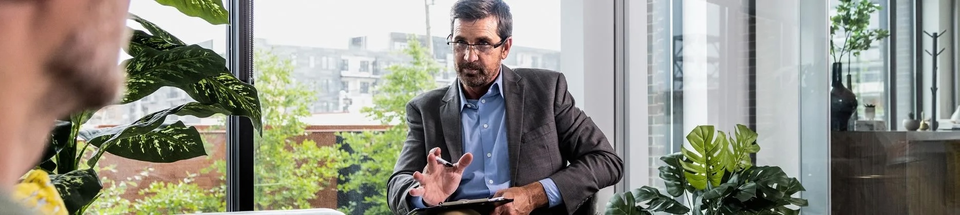 person sitting in chair in office with glass window behind them
