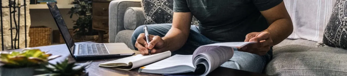 person sitting on sofa working on school work at coffee table