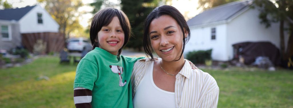 military spouse holding their child in front yard with green grass