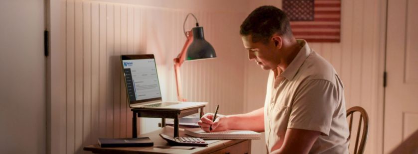 person sitting at desk working on NU school work with American flag on wall