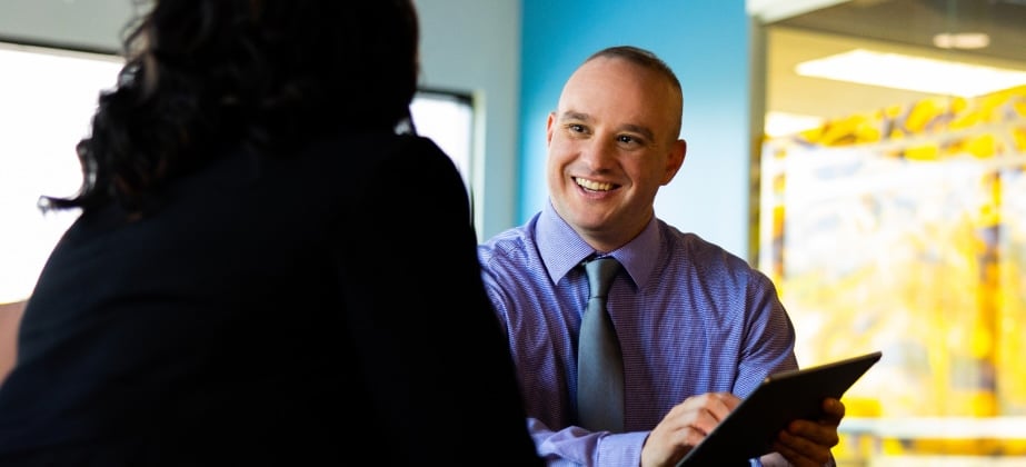 Man on tablet talking to woman in office