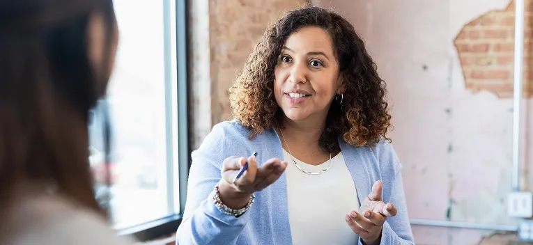 two people in office talking with brick wall behind them