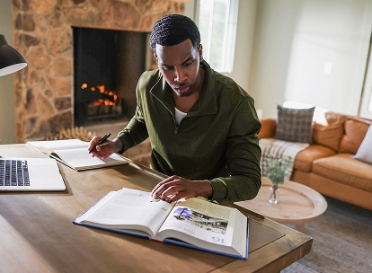military veteran working on laptop at desk with fireplace in background