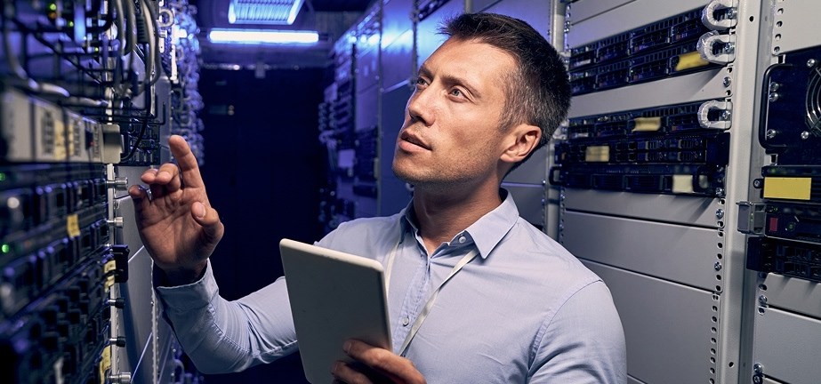guy holding tablet working in server room