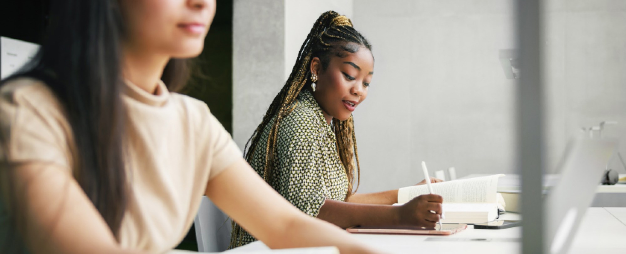 two people sitting at shared desk working on school work
