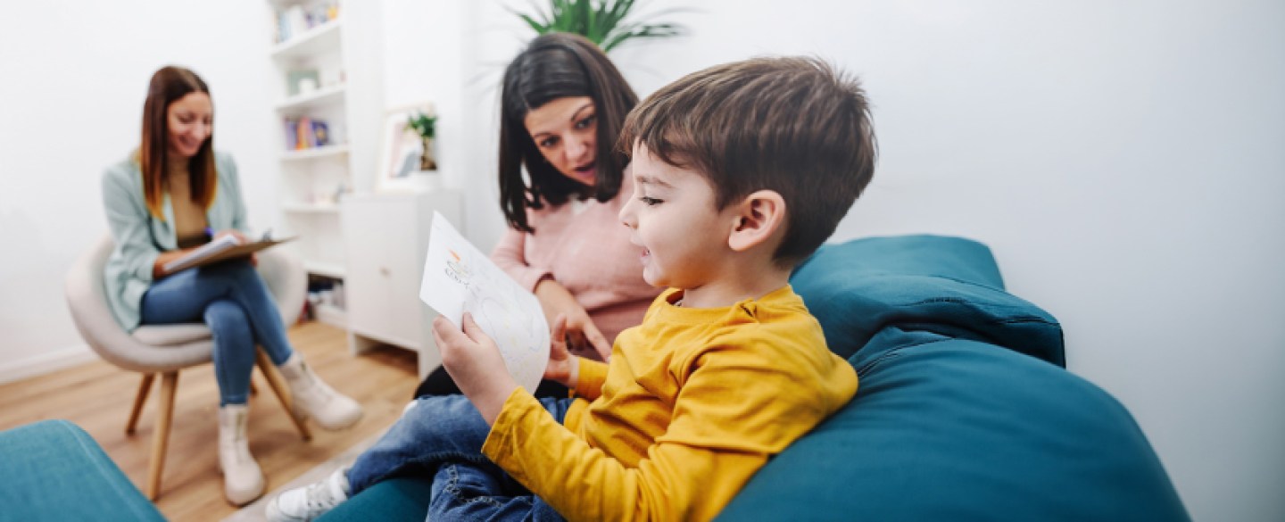 child reading in room with mother and psychologist
