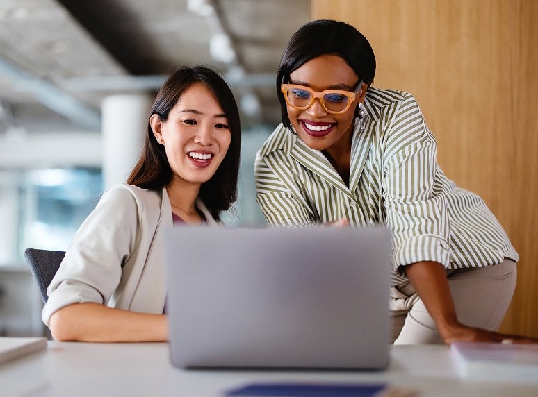 two people looking at laptop on desk