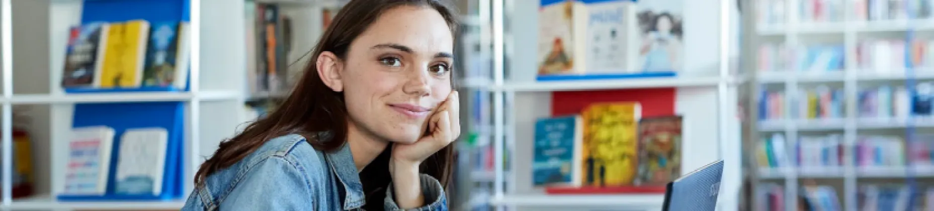 Confident young female student sitting at desk