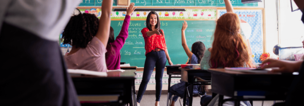 A school teacher standing in front of her classroom asking questions of the students